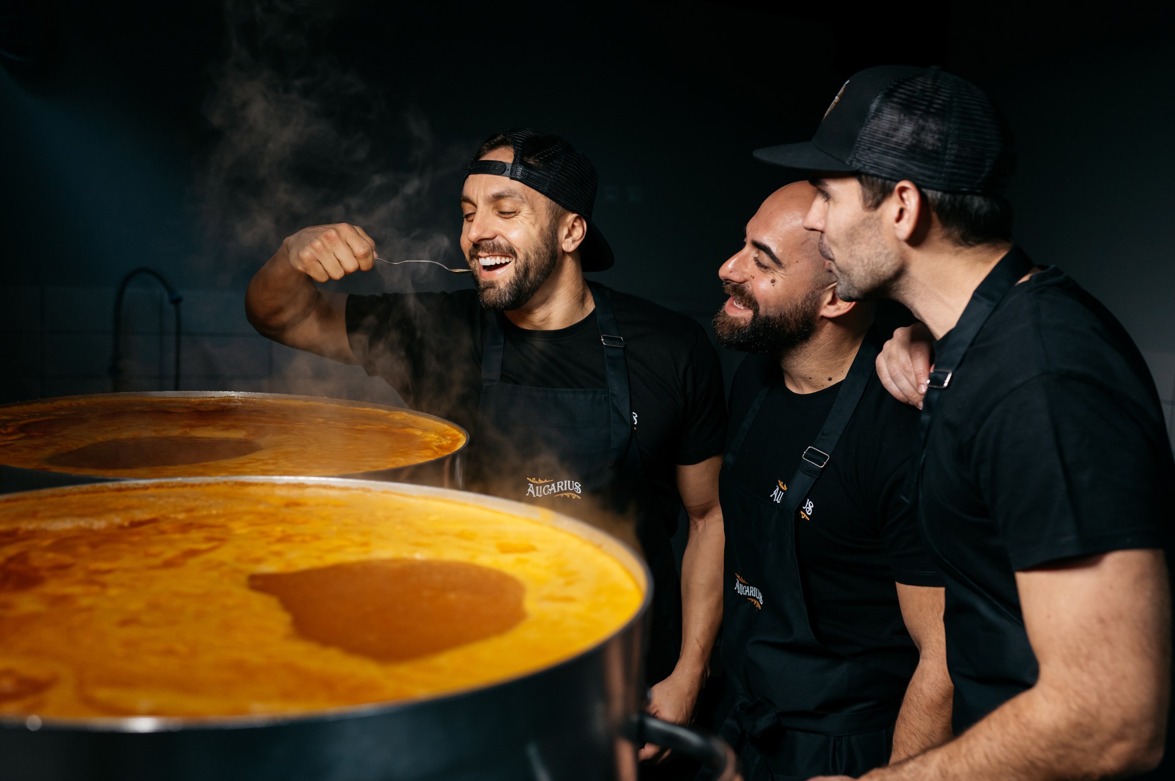 Os três sócios junto à panela do molho, um deles a provar com uma colher
