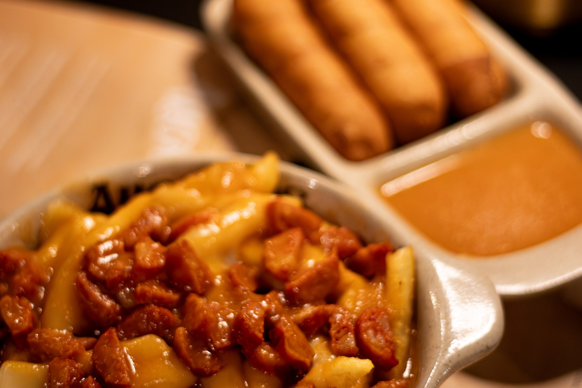 Tequeños com molho e uma taça de batatas com chouriço